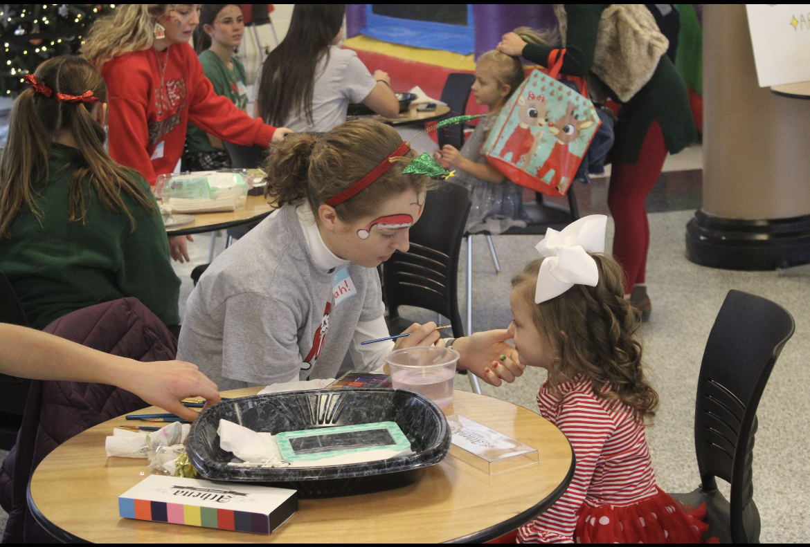 Senior Sarah Hoffman concentrated on making a perfect reindeer face-paint on a little girl  
