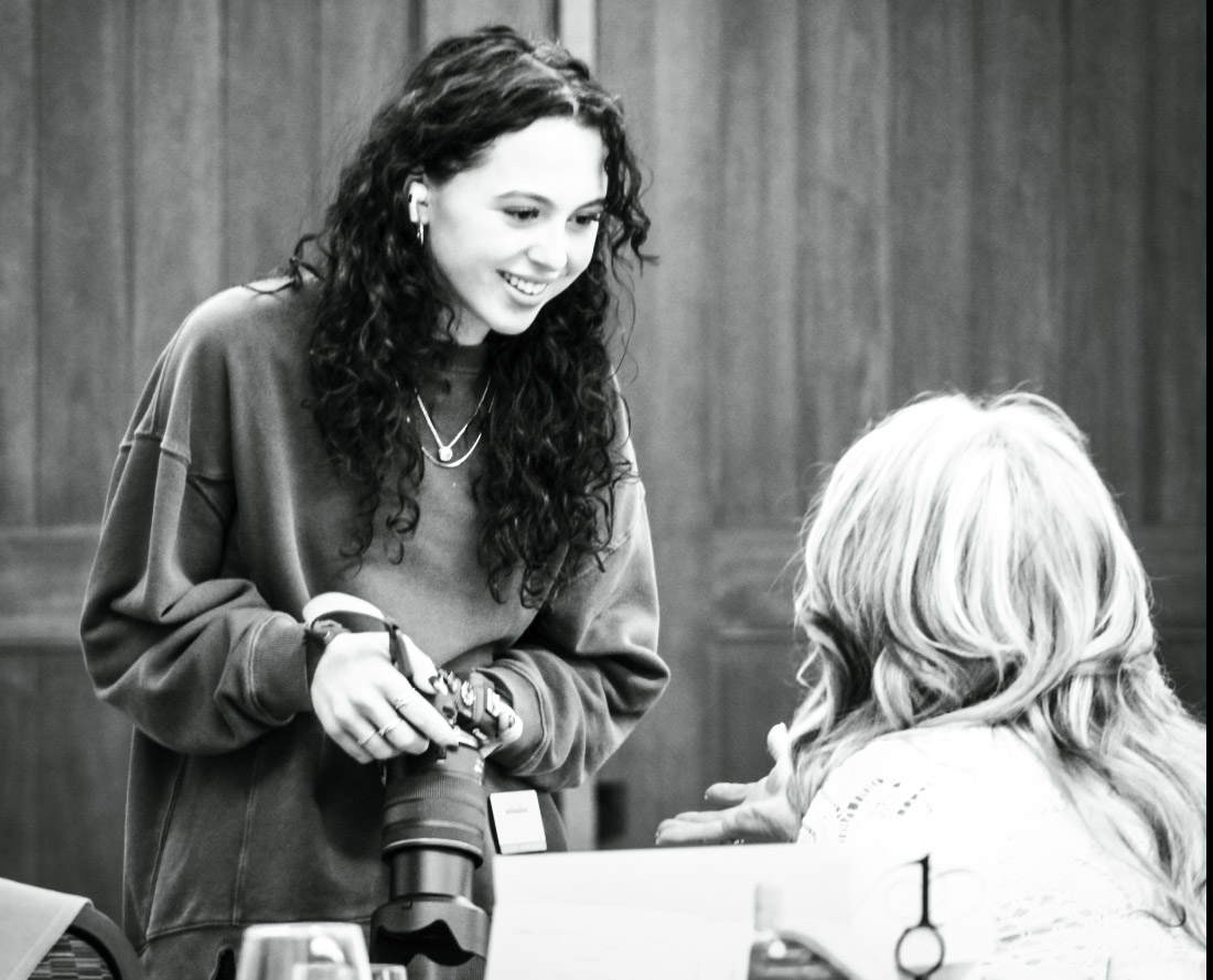 Madison Snyder, editor, talking to a woman while taking photos at the Loyal & True celebration. 